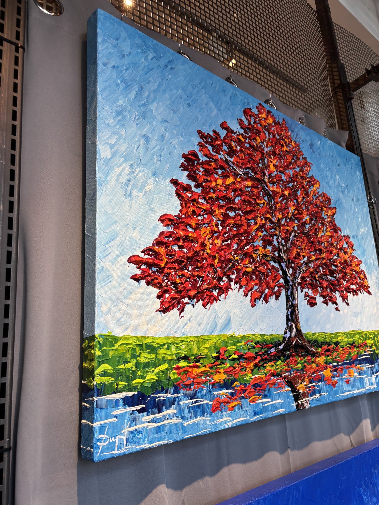 Colorful painting of a red tree on a blue sky background by Isabelle Dupuy