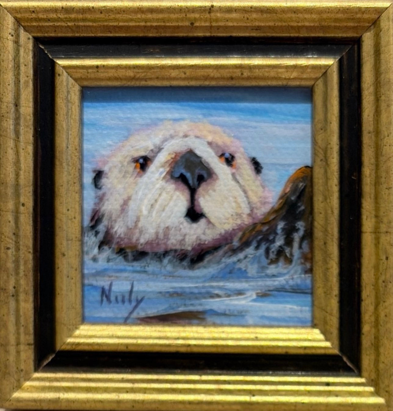 Otter original acrylic painting by Karen Neely featuring a close-up portrait of a curious sea otter floating in calm blue water, custom framed in an Italian gold moulding.