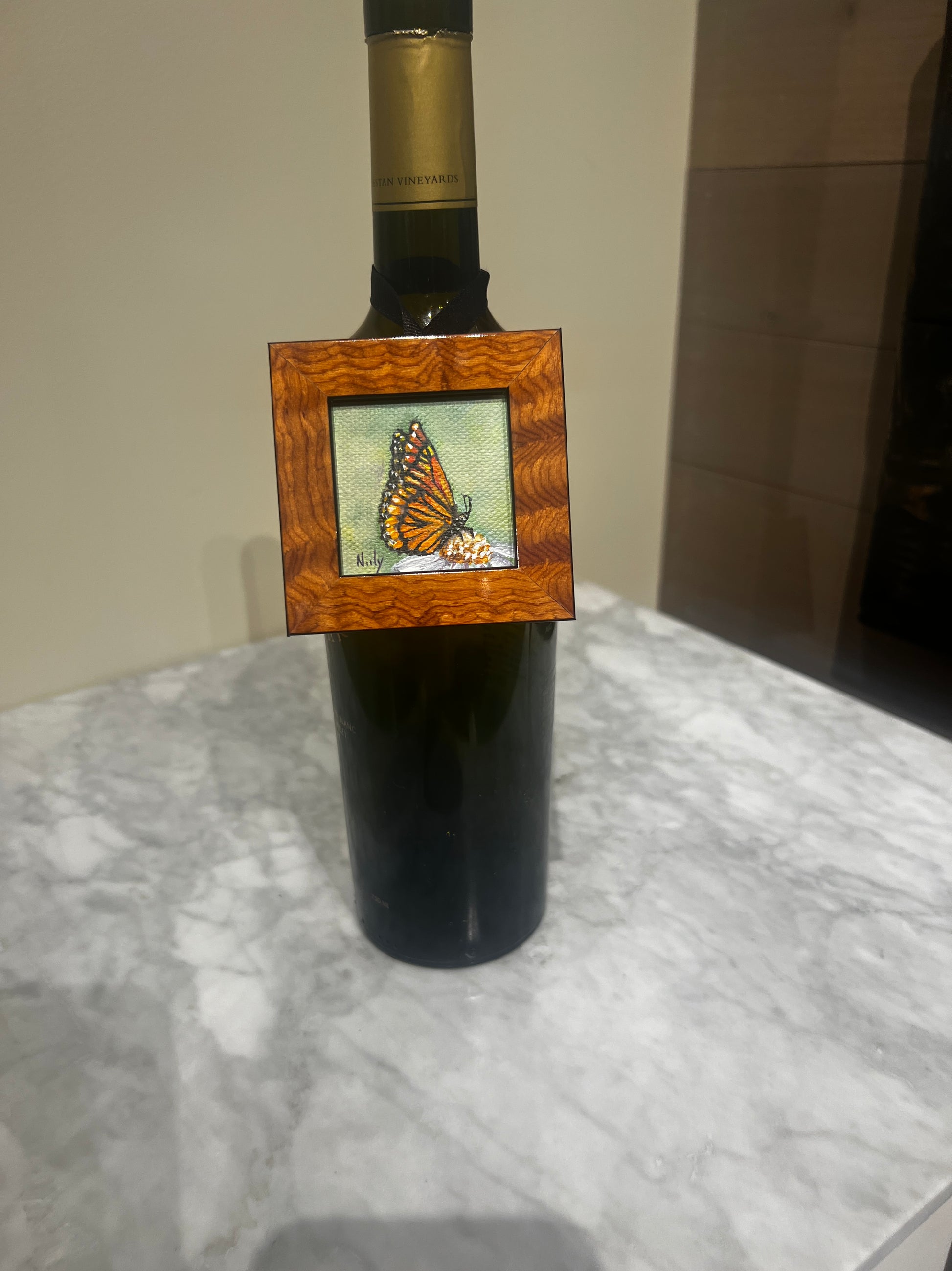 Miniature butterfly painting by Karen Neely in burl wood frame hanging on wine bottle