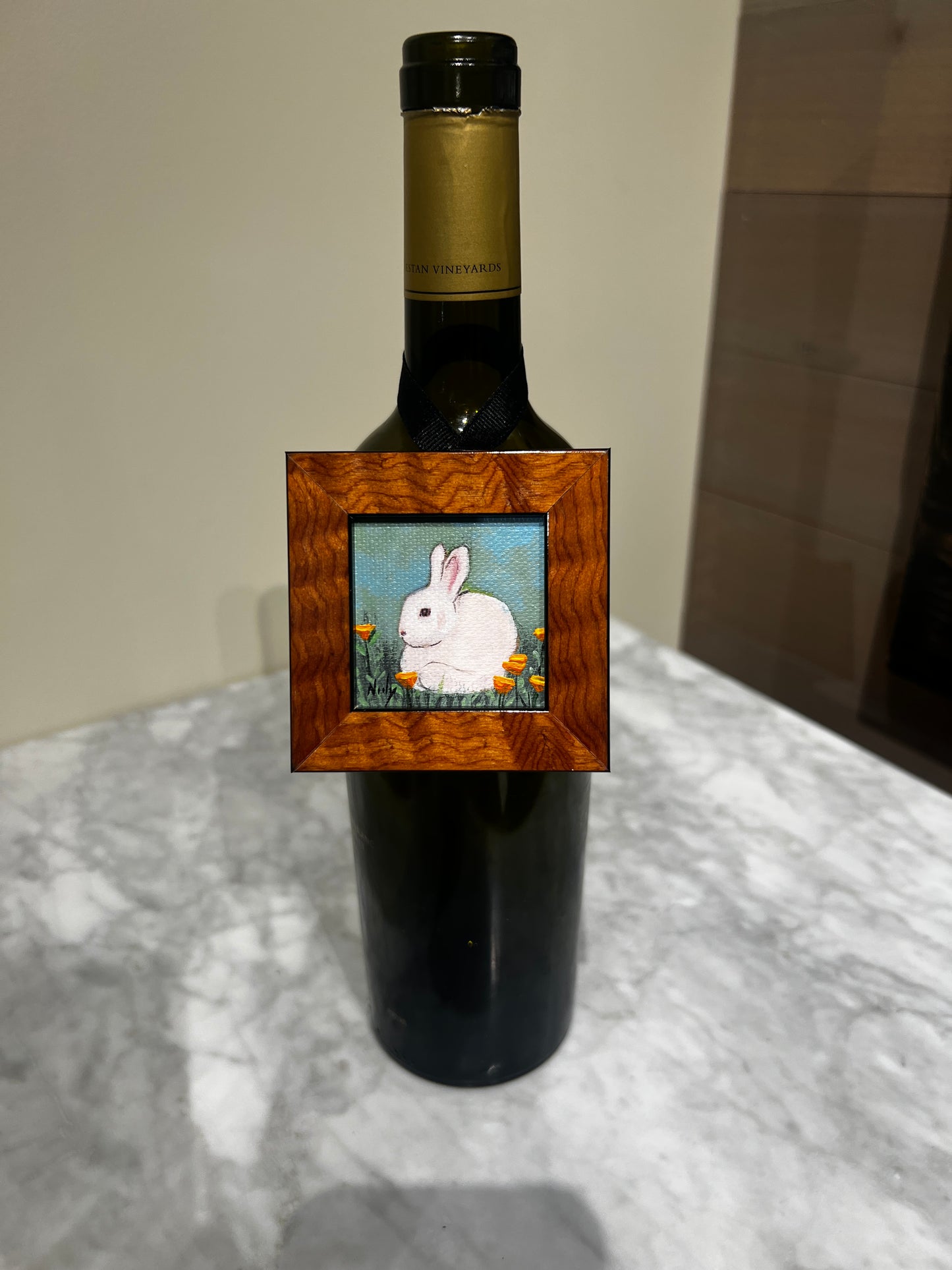 Bunny miniature painting by Karen Neely hanging on wine bottle